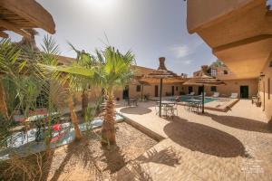 a patio with tables and umbrellas and a swimming pool at L'homme Du Désert A Merzouga in Merzouga