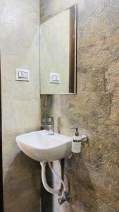ein weißes Waschbecken im Bad mit Spiegel in der Unterkunft Luxurious 3 BHK Villa In Bhuj - Shivani Homestay in Bhuj