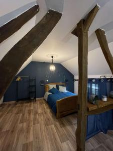 Blicourt的住宿－Les Gites de l'Herperie，一间卧室配有一张带蓝色墙壁和木梁的床。