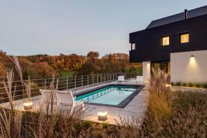 een zwart huis met een zwembad ervoor bij Chambres d’hôtes les Grisons in Houyet
