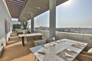 un restaurante con mesas y sillas en un balcón en A&H Hotel Apartment, en Doha
