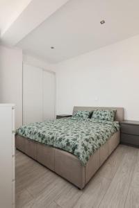 a white bedroom with a bed with a green blanket at Ambassador Apartment in Baia Mare