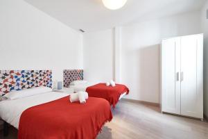 1 dormitorio con 2 camas con sábanas rojas y toallas blancas en Apartamento ideal para familias en Granada, en Granada