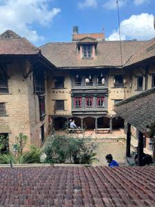 Newa Chen Historic House UNESCO في باتان: مبنى قديم فيه ولد جالس امامه