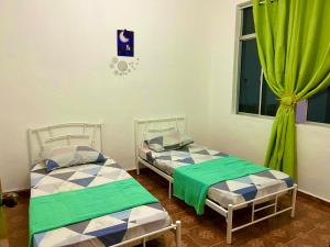 - 2 lits dans une chambre avec des rideaux verts dans l'établissement D'YELLOW HOMESTAY KANGAR PERLIS, à Kangar