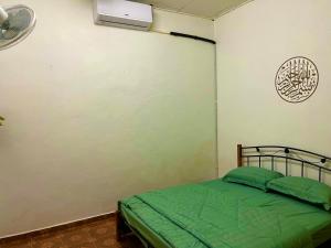 - une chambre avec un lit vert et un ventilateur dans l'établissement D'YELLOW HOMESTAY KANGAR PERLIS, à Kangar