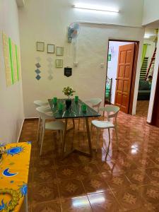une salle à manger avec une table en verre et des chaises blanches dans l'établissement D'YELLOW HOMESTAY KANGAR PERLIS, à Kangar