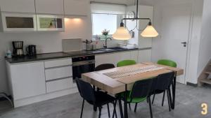 cocina con mesa de madera y sillas verdes en Sikory Hill en Czaplinek