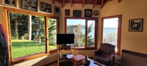 uma sala de estar com janelas grandes e uma televisão em A orillas del lago, un espacio para tu tranquilidad em San Carlos de Bariloche