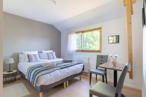 a bedroom with a bed and a table and a window at La Petite Croix Bienvenue in Saint-Cast-le-Guildo