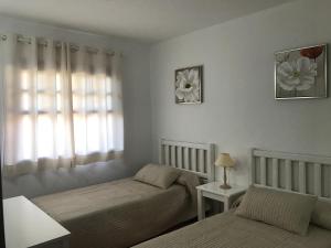 1 dormitorio con 2 camas y ventana en Royal park albatros bonito apartamento Golf del Sur, en San Miguel de Abona