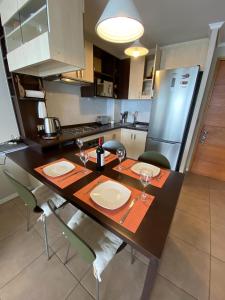 uma cozinha com uma mesa com pratos e copos de vinho em Maravilloso departamento con vista panorámica. em Concón