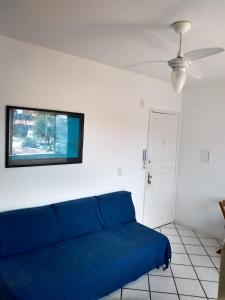 a blue couch in a room with a tv on the wall at Apartamento em Canasvieiras in Florianópolis