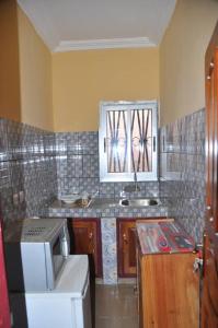 a small kitchen with a sink and a refrigerator at Appartements meublés haut Standing in Bertoua