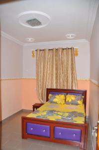 um quarto com uma cama e uma janela com lençóis amarelos em Appartements meublés haut Standing em Bertoua