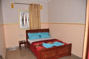 a bedroom with a bed with blue pillows and a window at Appartements meublés haut Standing in Bertoua