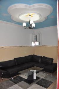 a living room with a black couch and a ceiling at Appartements meublés haut Standing in Bertoua