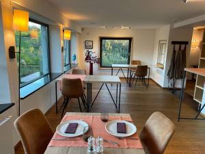 uma sala de jantar com mesas, cadeiras e janelas em Chambres d’hôtes les Grisons em Houyet