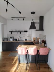 uma cozinha com uma mesa de madeira e 2 cadeiras cor-de-rosa em Apartament Słoneczny 2 em Sanok