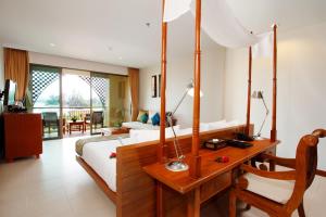 ein Schlafzimmer mit einem Bett und einem Schreibtisch in einem Zimmer in der Unterkunft Rawai Palm Beach Resort - SHA Extra Plus in Rawai Beach