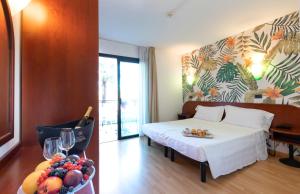 una camera d'albergo con letto e cesto di frutta di Hotel Falcone a Lignano Sabbiadoro