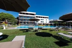 un hotel con piscina, sedie e ombrelloni di Hotel Falcone a Lignano Sabbiadoro