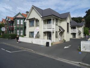 uma mulher a andar numa rua em frente a uma casa em Sahara Motels em Dunedin