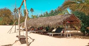 a straw hut on a beach with chairs and palm trees at Lagoon Paradise Beach Resort in Tangalle