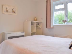 a white bedroom with a bed and a window at Barn Owls Holiday Bungalow in Salcombe Regis
