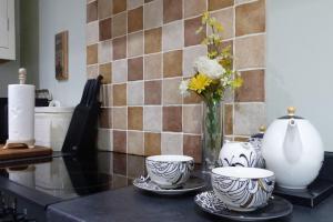 a kitchen counter with two cups and a vase with flowers at Sunset View a quiet and romantic rural retreat for 2 adults just outside ingleton in Ingleton