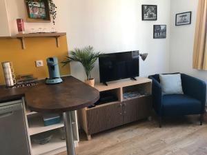 a living room with a table and a television at Le Petit Nid d'Honfleur in Honfleur