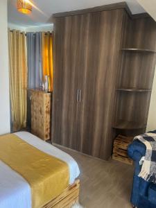 a bedroom with a bed and a wooden cabinet at Ruby Modern Homes Studio-Imara Daima,Behind Imaara Mall-JKIA-Horizon in Nairobi