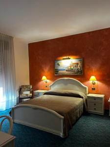 sypialnia z dużym łóżkiem z pomarańczowymi ścianami w obiekcie Hotel Rey's w mieście Montegrotto Terme