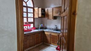 una pequeña cocina con armarios de madera y una ventana en Ouirgane House, en Ouirgane