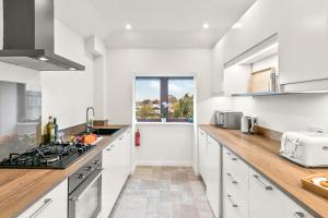 cocina con armarios blancos y encimera en Aspen Apartment en Helensburgh