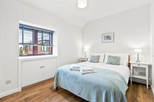 a white bedroom with a bed and a window at Aspen Apartment in Helensburgh