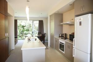 a kitchen with a white refrigerator and a table at Oceans Resort Whitianga in Whitianga