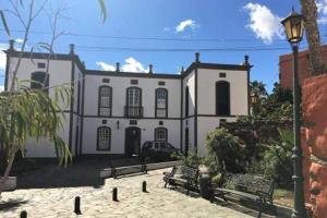 a large white building with benches in front of it at El Puente Holiday Home-II 8,1Kms Airport in Ingenio