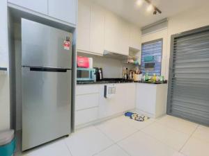 una cocina con nevera de acero inoxidable y armarios blancos en Double Storey Sweet Home 12pax @ Puncak Alam, en Kuala Selangor