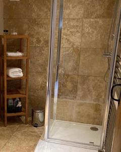 um chuveiro com uma porta de vidro na casa de banho em Dallow Hall Barns em Grantley