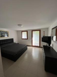 a bedroom with a black bed and a flat screen tv at La casa di Chicca in Noventa Padovana