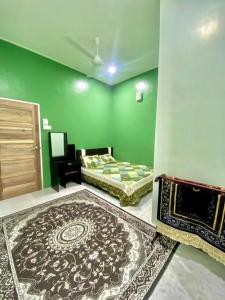 een groene kamer met 2 bedden en een tapijt bij Homestay Kak Tiy in Kuala Terengganu