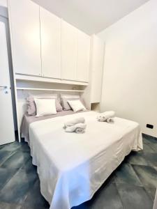 a white bedroom with two beds with towels on them at A 5 minuti dal mare - Dolphin Beach House in Spotorno