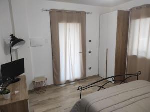 ein Schlafzimmer mit einem Bett und einem Fernseher in der Unterkunft S' apossentu in Fonni