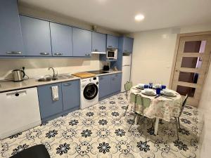 a kitchen with blue cabinets and a table with a laundry at Alojamiento Lope de Fenar in León
