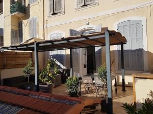 a wooden pergola on a patio with tables and chairs at Superbe 2 pièces avec grande terrasse, classé *** in Marseille