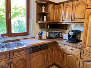a kitchen with wooden cabinets and a sink and a microwave at Messe- & Ferienhaus Gertraud am Ludwigskanal, 24 h Self Check-In, Gratis parken in Wendelstein