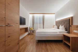 a bedroom with a white bed and a wooden floor at Klimahaus Dep. La Fradora in San Cassiano