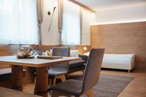a dining room with a table and chairs and a bed at Klimahaus Dep. La Fradora in San Cassiano