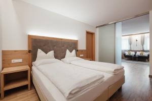 a bedroom with a large white bed and a living room at Klimahaus Dep. La Fradora in San Cassiano